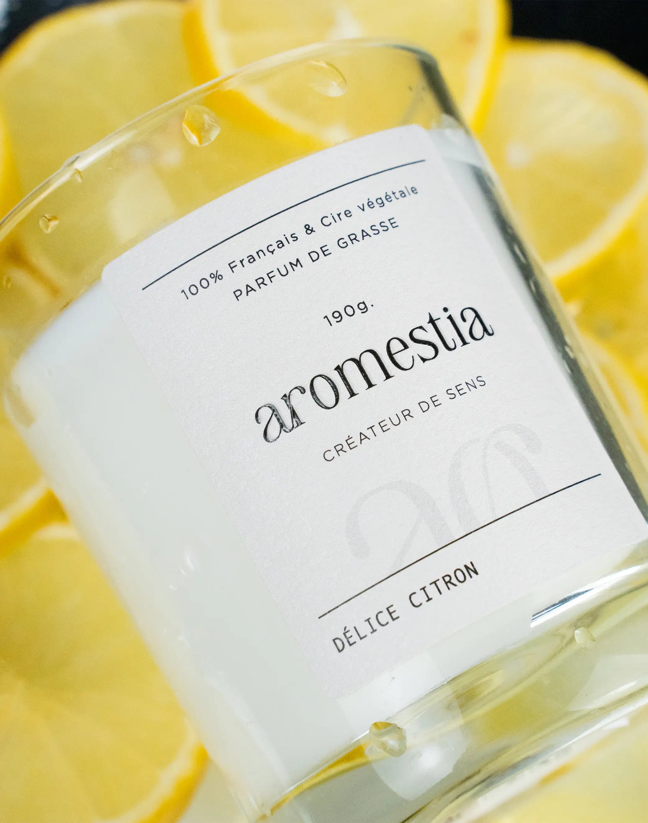 Bougie au citron Aromestia avec un contenant transparent et des citrons en arrière-plan