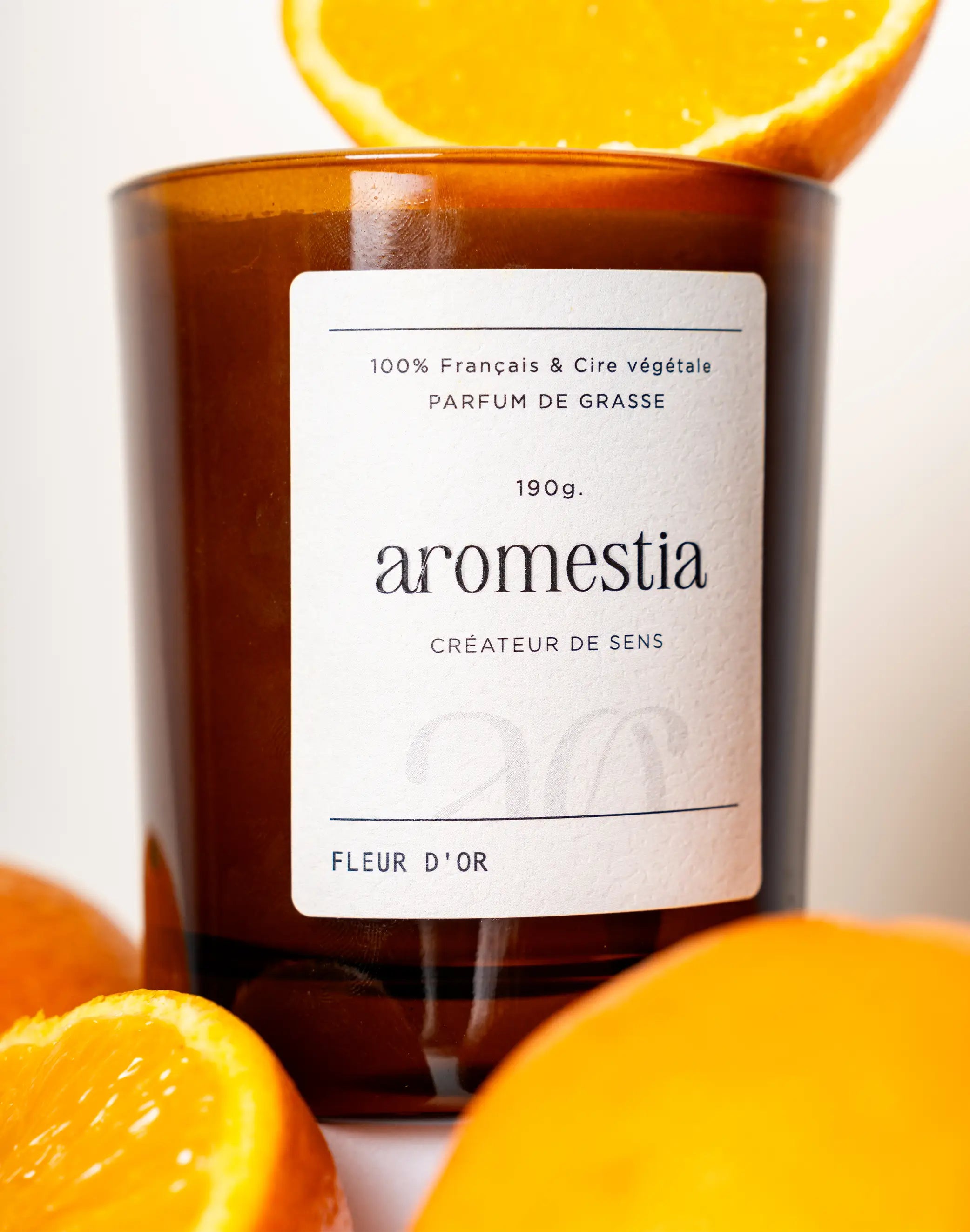 Bougie fleur d'oranger avec contenant ambré Aromestia et des oranges autour